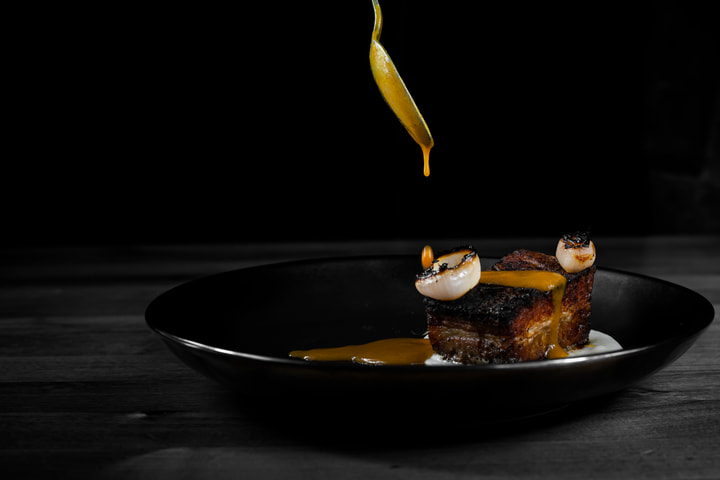 Sauce poured over plated pork belly