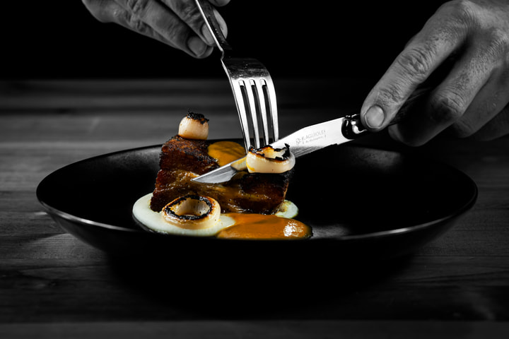 Knife and fork cutting into pork belly