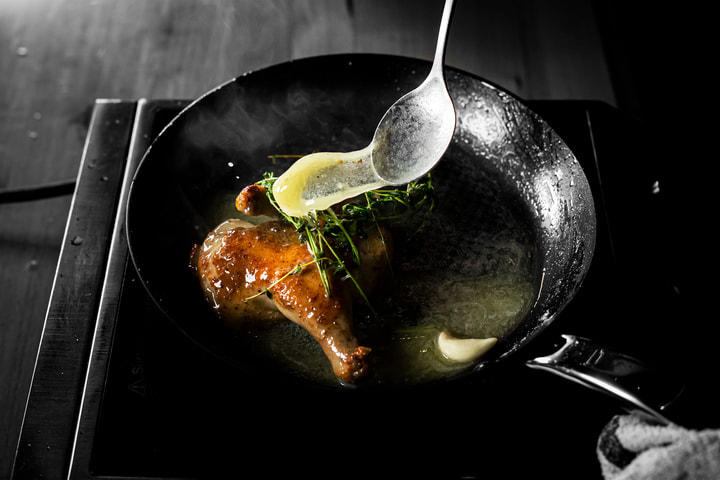Butter spooned over a hen in a skillet