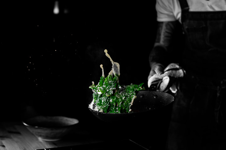 Tongs lifting greens from a pan