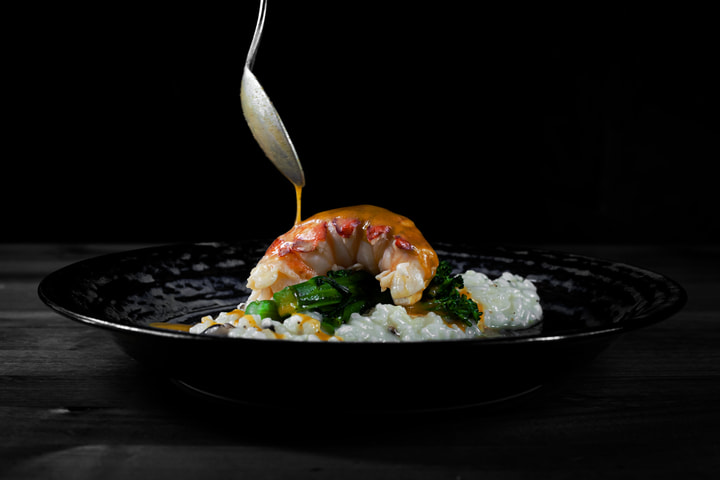 Sauce spooned over lobster on risotto