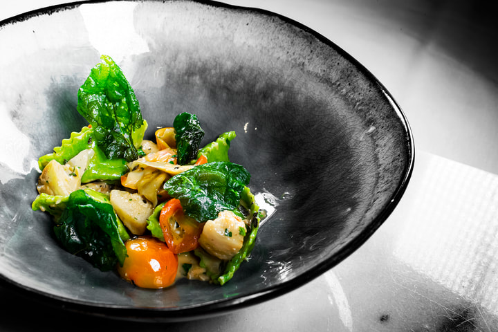 Pasta with greens and tomatoes in a stoneware bowl