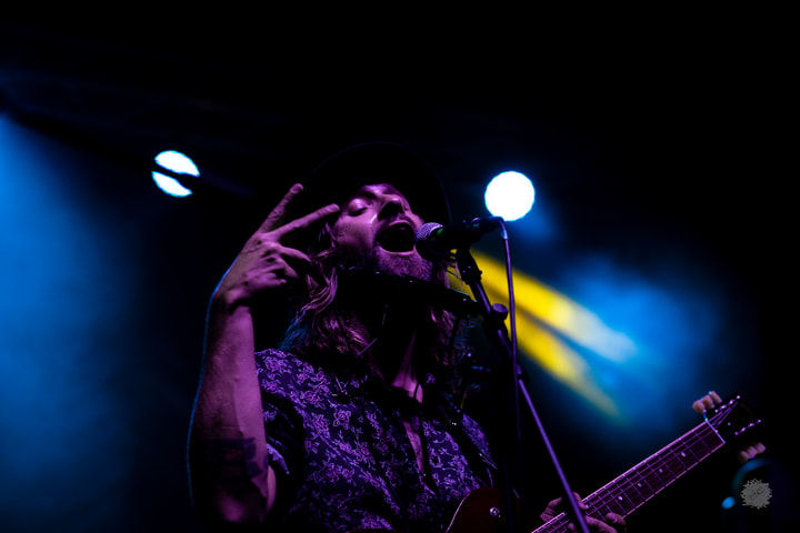 Guitarist gesturing under blue light