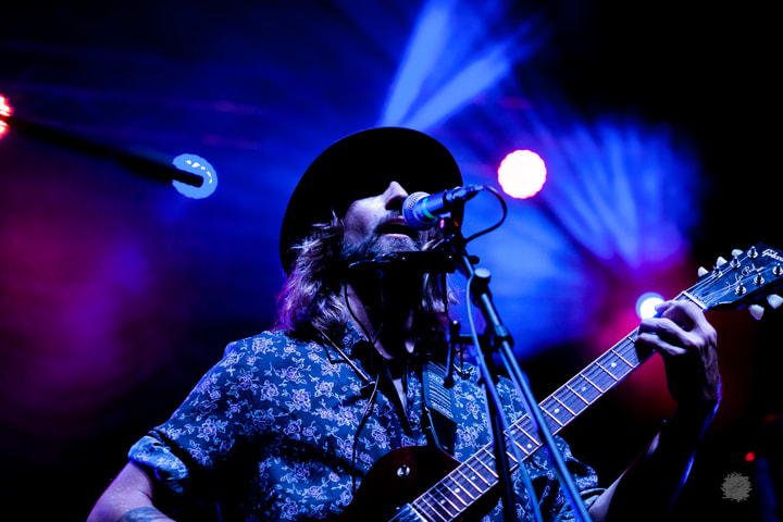 Guitarist singing under blue and pink light