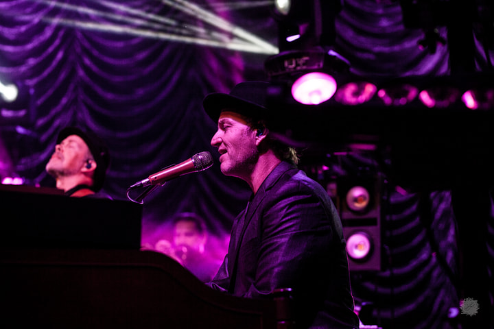 Keyboard player singing under purple light