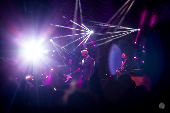 Band under white and purple light beams