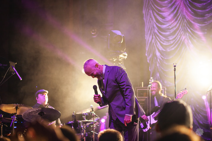 Singer leaning toward the crowd in warm haze