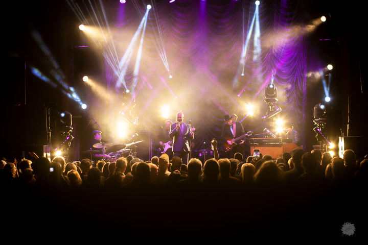 Band on a lit stage in front of a crowd